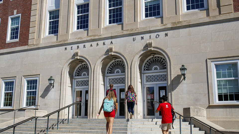 Fours students walk towards the Nebraska Union's south entrance doors.