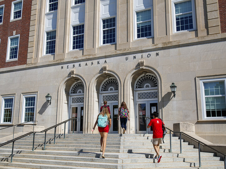 Fours students walk towards the Nebraska Union's south entrance doors.